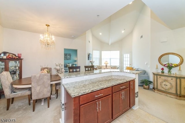 kitchen with light carpet, a kitchen island, light stone counters, hanging light fixtures, and a chandelier