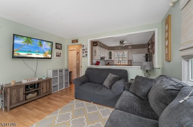 living room with visible vents, light wood-type flooring, and a ceiling fan