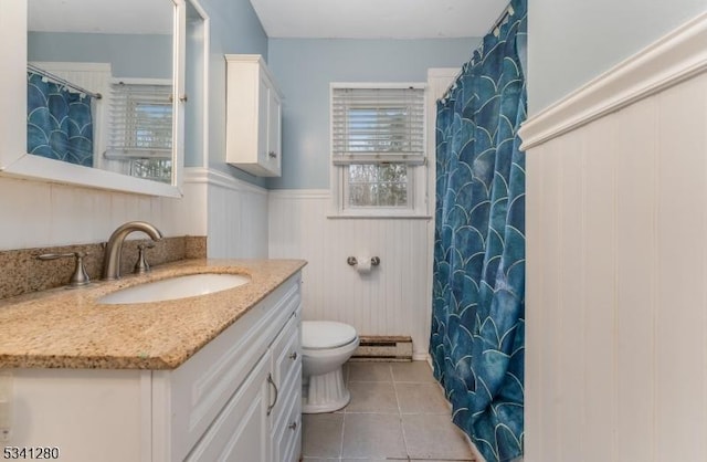 bathroom with a wainscoted wall, toilet, baseboard heating, vanity, and tile patterned floors