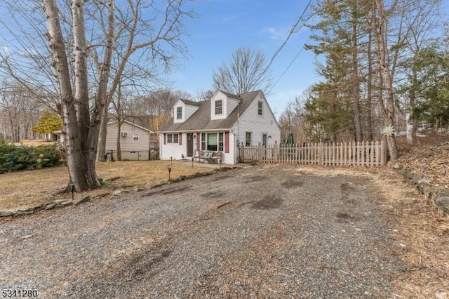 cape cod home with driveway and fence