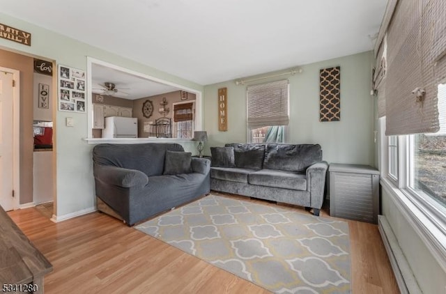 living area featuring light wood finished floors, a baseboard radiator, and baseboards