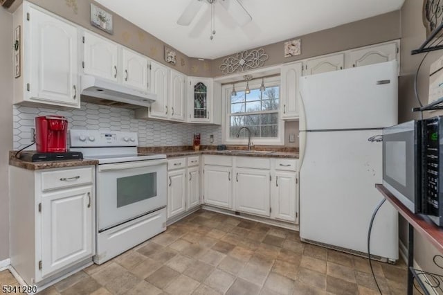 kitchen with under cabinet range hood, white appliances, a sink, white cabinetry, and dark countertops