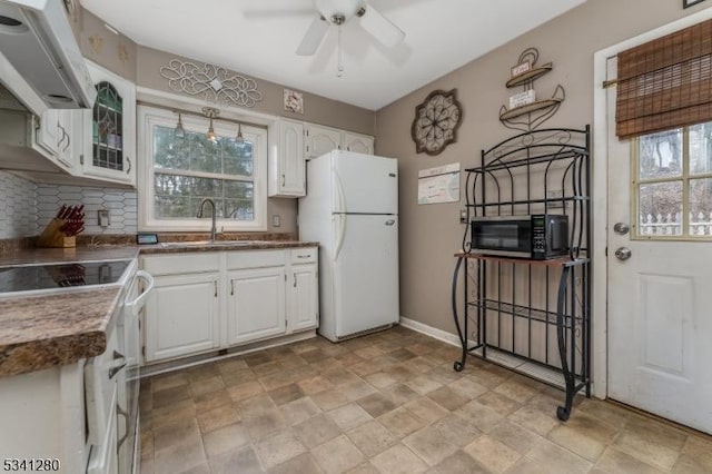 kitchen with freestanding refrigerator, white cabinets, a sink, and range hood