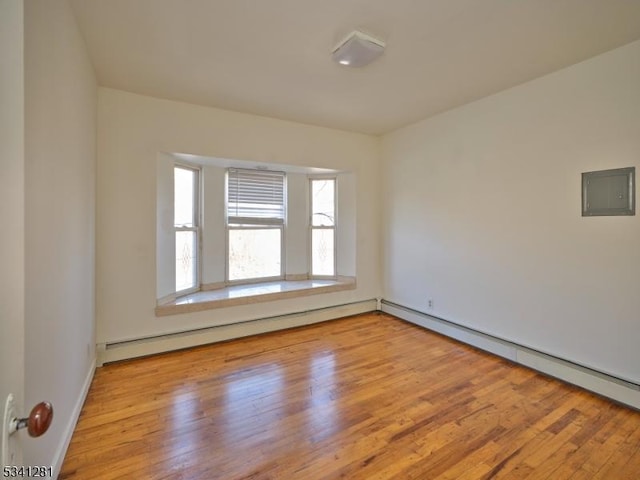 unfurnished room featuring electric panel, baseboard heating, and wood finished floors