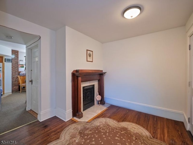 living room featuring a fireplace with flush hearth, baseboards, and wood finished floors