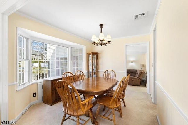 dining room with light carpet, visible vents, a notable chandelier, and ornamental molding