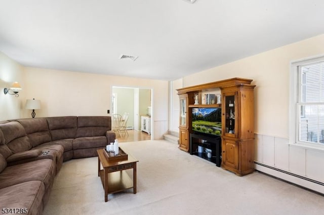 living room with visible vents, baseboard heating, a healthy amount of sunlight, and light colored carpet