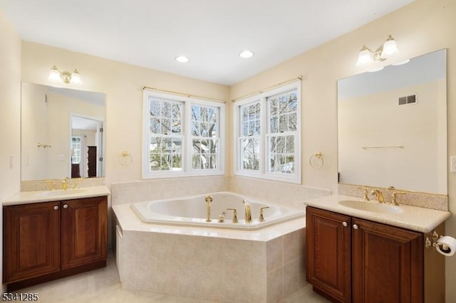 full bath with a bath, two vanities, and a sink