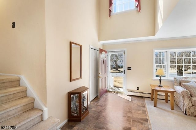 entryway with stairs, plenty of natural light, and a towering ceiling