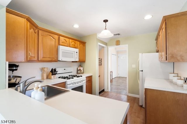 kitchen with a sink, visible vents, white appliances, and light countertops