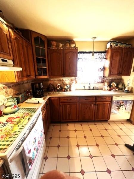 kitchen featuring pendant lighting, light floors, light countertops, a sink, and under cabinet range hood