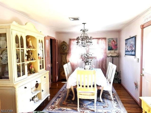 dining space featuring visible vents, dark wood finished floors, a notable chandelier, and ornamental molding