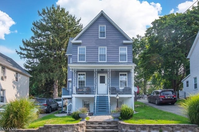 view of front facade with a front yard, covered porch, and stairway