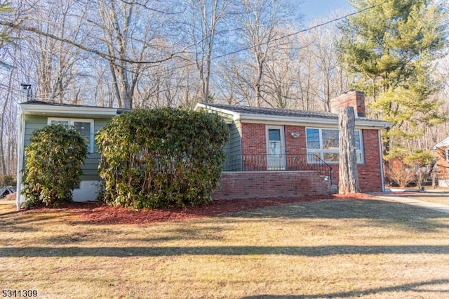 view of front of property with crawl space, a front lawn, a chimney, and brick siding