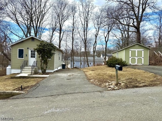 exterior space with entry steps, driveway, an outdoor structure, and a shed