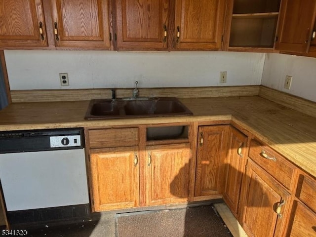 kitchen featuring brown cabinetry, light countertops, dishwasher, and a sink