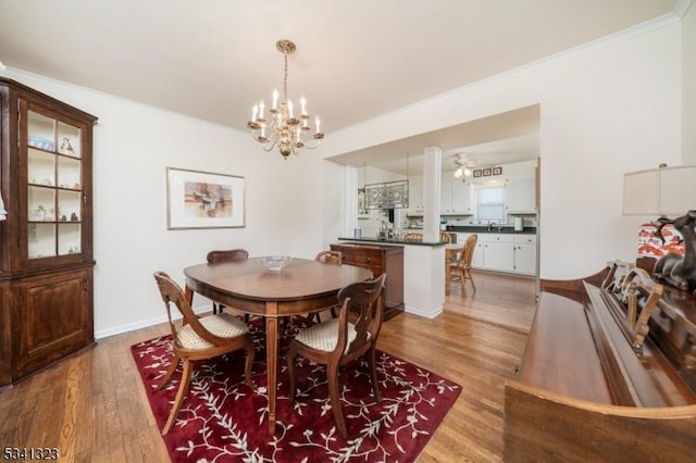 dining room with an inviting chandelier, baseboards, ornamental molding, and wood finished floors