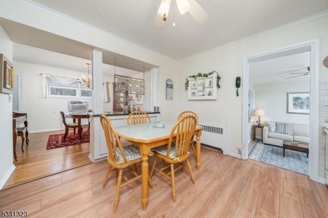 dining area with crown molding, light wood finished floors, radiator heating unit, and ceiling fan with notable chandelier