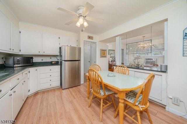 kitchen with stainless steel appliances, dark countertops, white cabinetry, and crown molding