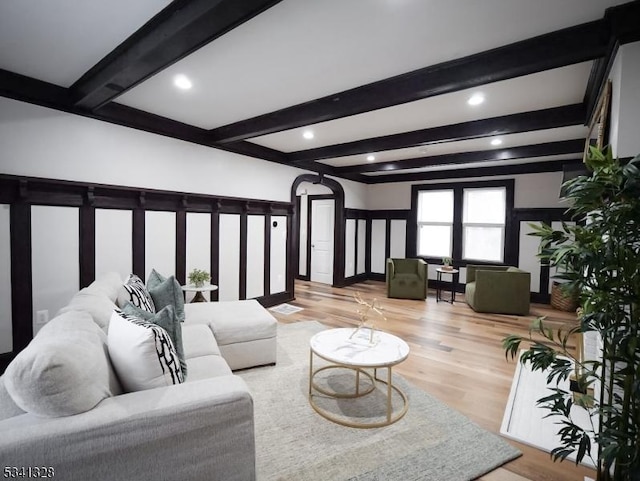 living room with beam ceiling, wood finished floors, and arched walkways