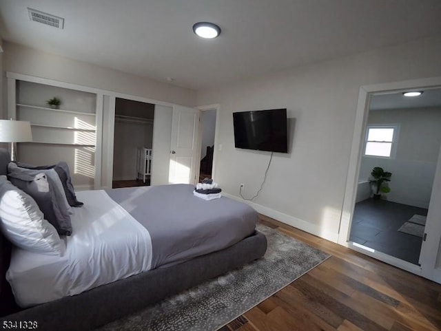 bedroom featuring wood finished floors, visible vents, and baseboards