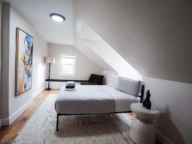 bedroom with lofted ceiling, wood finished floors, and baseboards