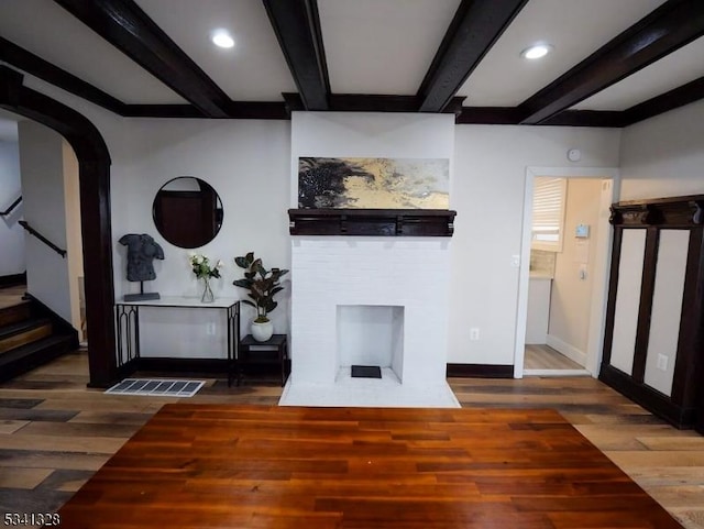 living area featuring baseboards, beam ceiling, stairway, and wood finished floors