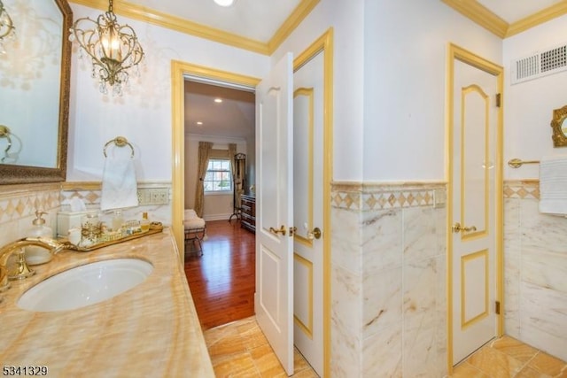 bathroom featuring a wainscoted wall, visible vents, crown molding, and tile walls