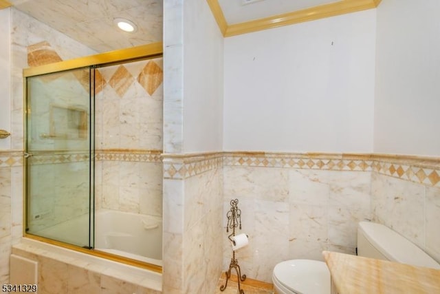 bathroom featuring toilet, ornamental molding, and combined bath / shower with glass door