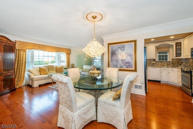 dining space featuring a chandelier, visible vents, crown molding, and wood finished floors