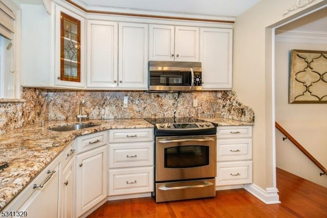 kitchen with stainless steel appliances, dark wood-style flooring, a sink, tasteful backsplash, and glass insert cabinets