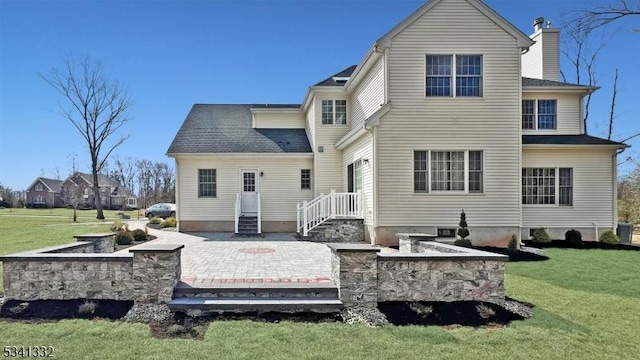 rear view of house with a patio area, a chimney, and a lawn