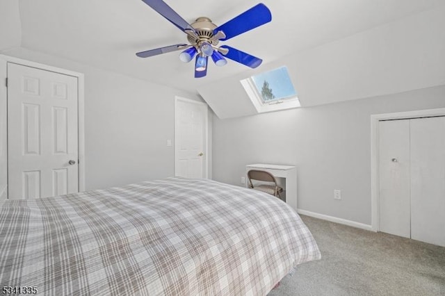 carpeted bedroom featuring lofted ceiling with skylight, a closet, a ceiling fan, and baseboards