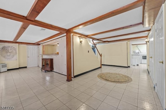 interior space with beamed ceiling, light tile patterned flooring, washer and clothes dryer, and baseboards