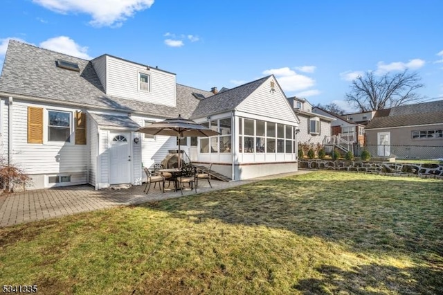 rear view of house featuring roof with shingles, a lawn, a sunroom, a patio area, and fence