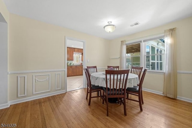 dining room with light wood-style floors, visible vents, and baseboards