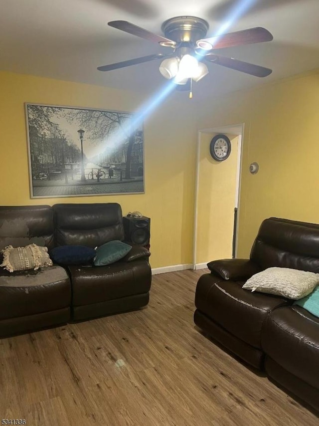 living area featuring a ceiling fan, baseboards, and wood finished floors