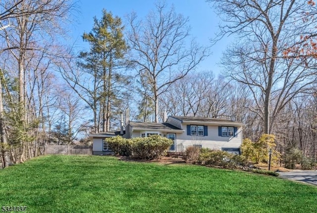 tri-level home with fence and a front lawn