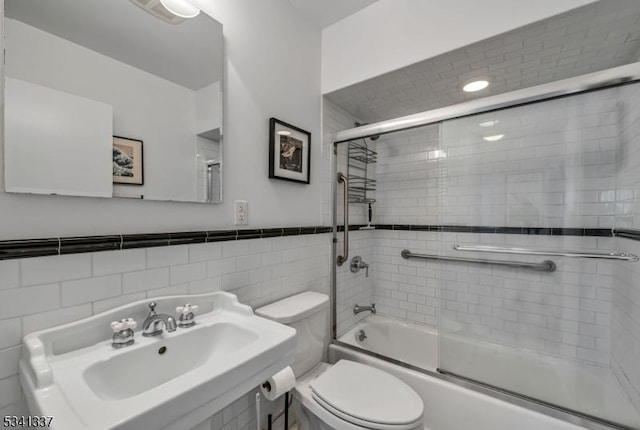 bathroom featuring enclosed tub / shower combo, toilet, a sink, visible vents, and tile walls