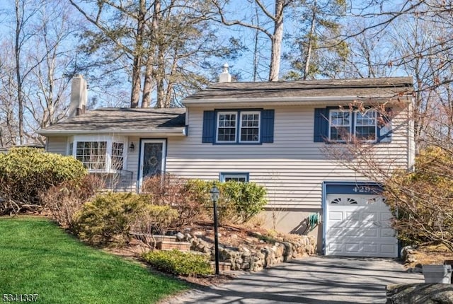 split level home featuring a garage, concrete driveway, and a chimney