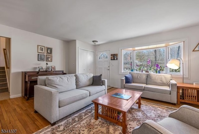 living area with light wood-style floors, baseboards, and stairway