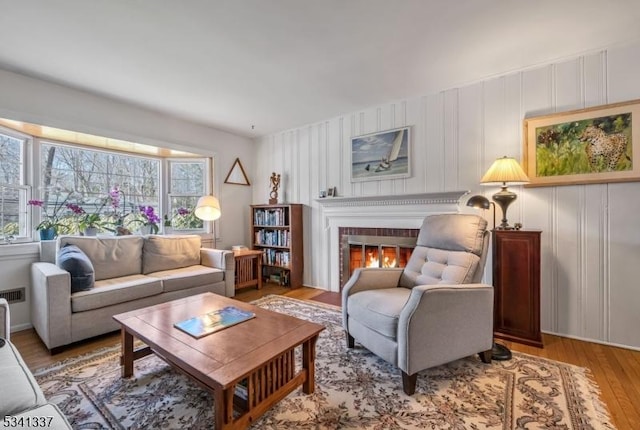 living area featuring wood finished floors and a glass covered fireplace