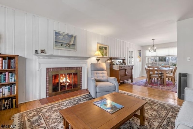 living area featuring a chandelier, a fireplace, and wood finished floors