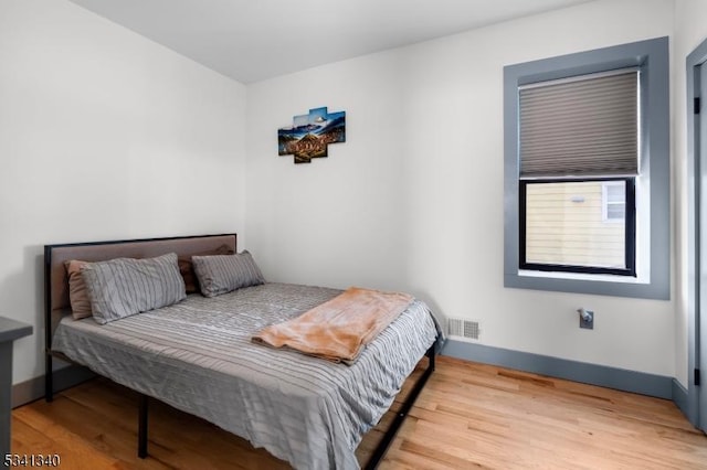 bedroom featuring visible vents, baseboards, and wood finished floors