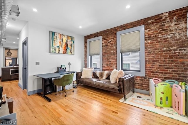 interior space with brick wall, recessed lighting, light wood-type flooring, and baseboards