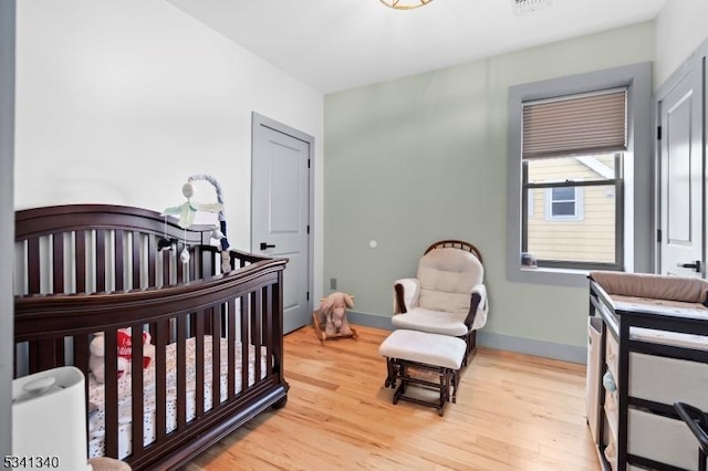 bedroom featuring a nursery area, wood finished floors, and baseboards