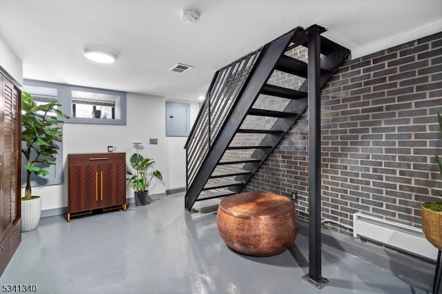 stairs featuring concrete flooring, brick wall, visible vents, and electric panel