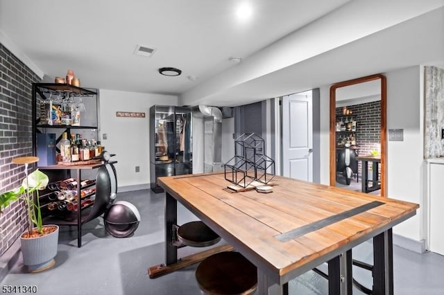 dining room with finished concrete floors, visible vents, and a dry bar