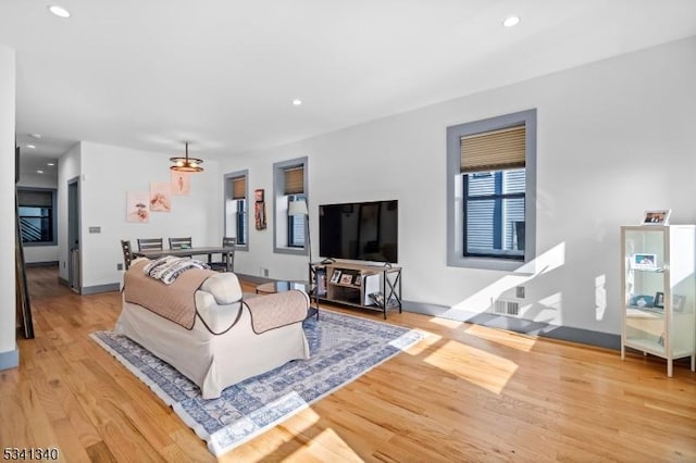 living room featuring visible vents, baseboards, wood finished floors, and recessed lighting