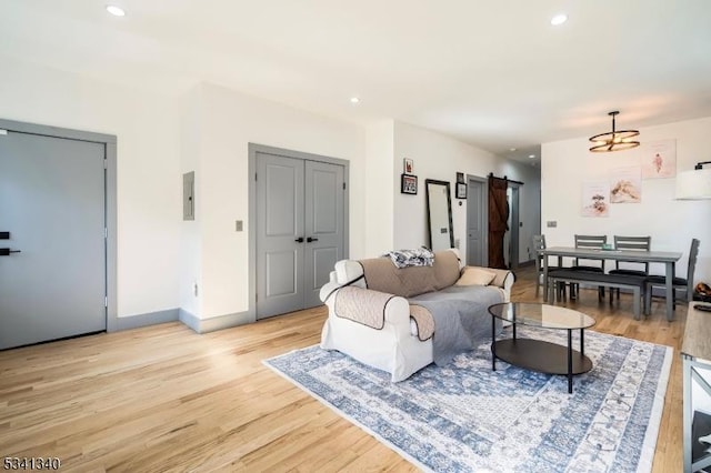 living area featuring recessed lighting, light wood-style flooring, baseboards, and a barn door